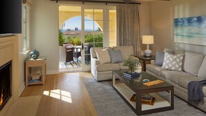 Un salon spacieux doté d’une cheminée, d’un canapé, d’une table basse et offrant une vue sur un patio aménagé avec du mobilier d’extérieur.