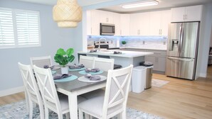 A modern kitchen with white cabinetry, stainless steel appliances, and a dining area with a table set for four.