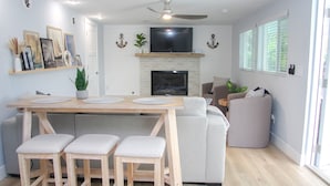 A modern kitchen with a dining area, a fireplace, and a ceiling fan.