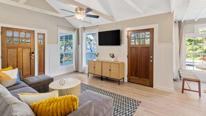 A spacious living room with a ceiling fan, a large TV mounted on the wall, and a wooden cabinet. - America's Lake Cabin with Patio & Firepit! (Nevada)