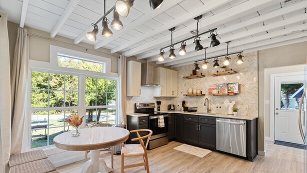 A modern kitchen with a large island, pendant lighting, and a view of the outdoors. - America's Lake Cabin with Patio & Firepit! (Nevada)