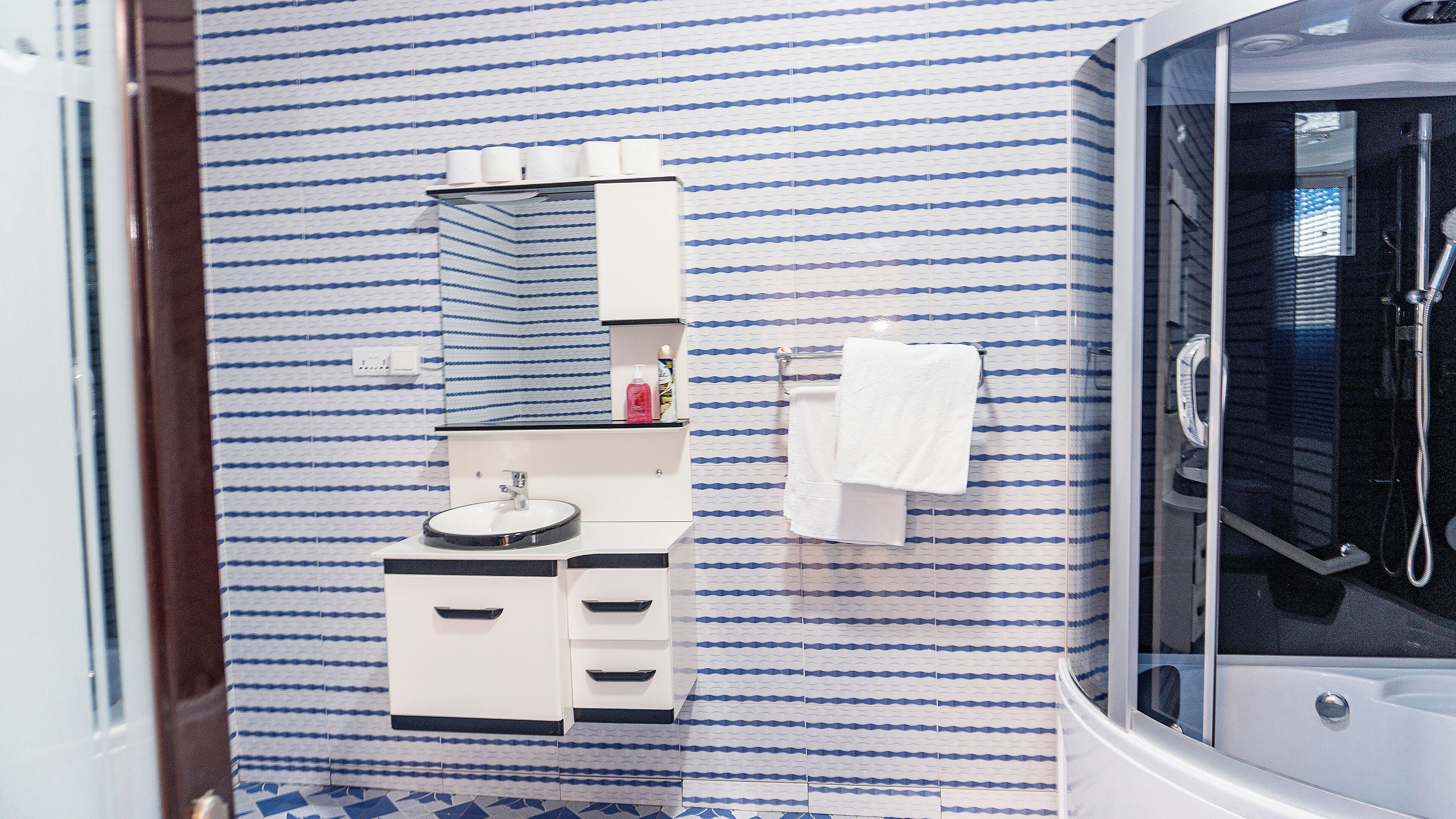 A modern bathroom with a vanity, sink, and a glass-enclosed shower area.
