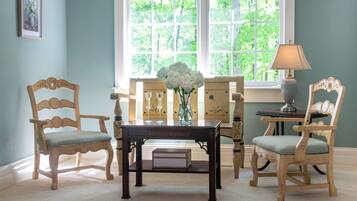 A room with a wooden table, two chairs, a vase with flowers, and a lamp.