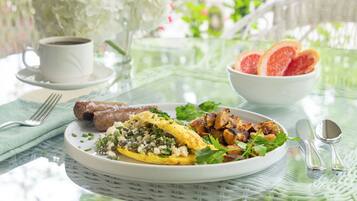 A breakfast setting with a plate of food, a cup of coffee, and a bowl of fruit.