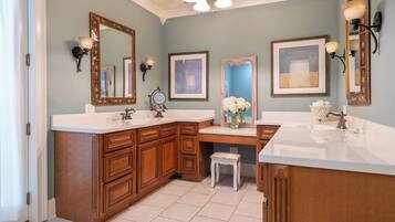A bathroom with two sinks, wooden cabinetry, and a vanity with a stool.