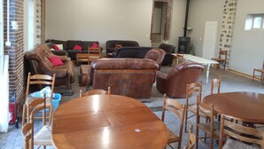 Un salón espacioso con una gran mesa de comedor de madera rodeada de sillas, un conjunto de sofá de cuero y una chimenea.