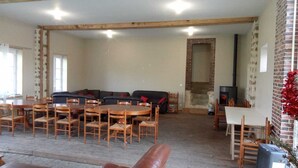 Un amplio salón con una mesa y sillas de madera, un sofá negro y una chimenea de ladrillo.