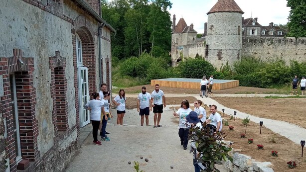 Un patio con un edificio histórico, plantas en macetas y un castillo al fondo.