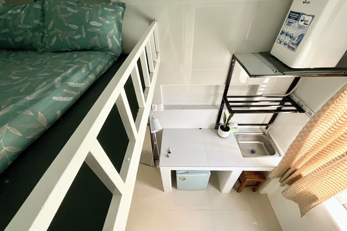 A compact kitchenette with a sink, a small refrigerator, and a white countertop.
