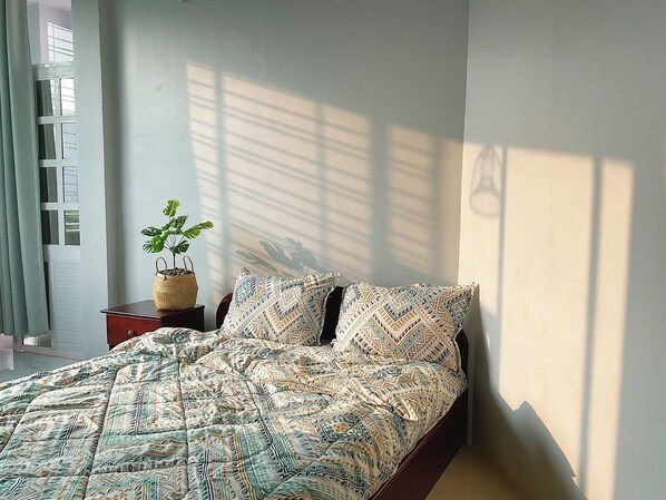 A bedroom with a bed, a potted plant, and a window with curtains. - HOANG CAM HOTEL (Ho Chi Minh City)
