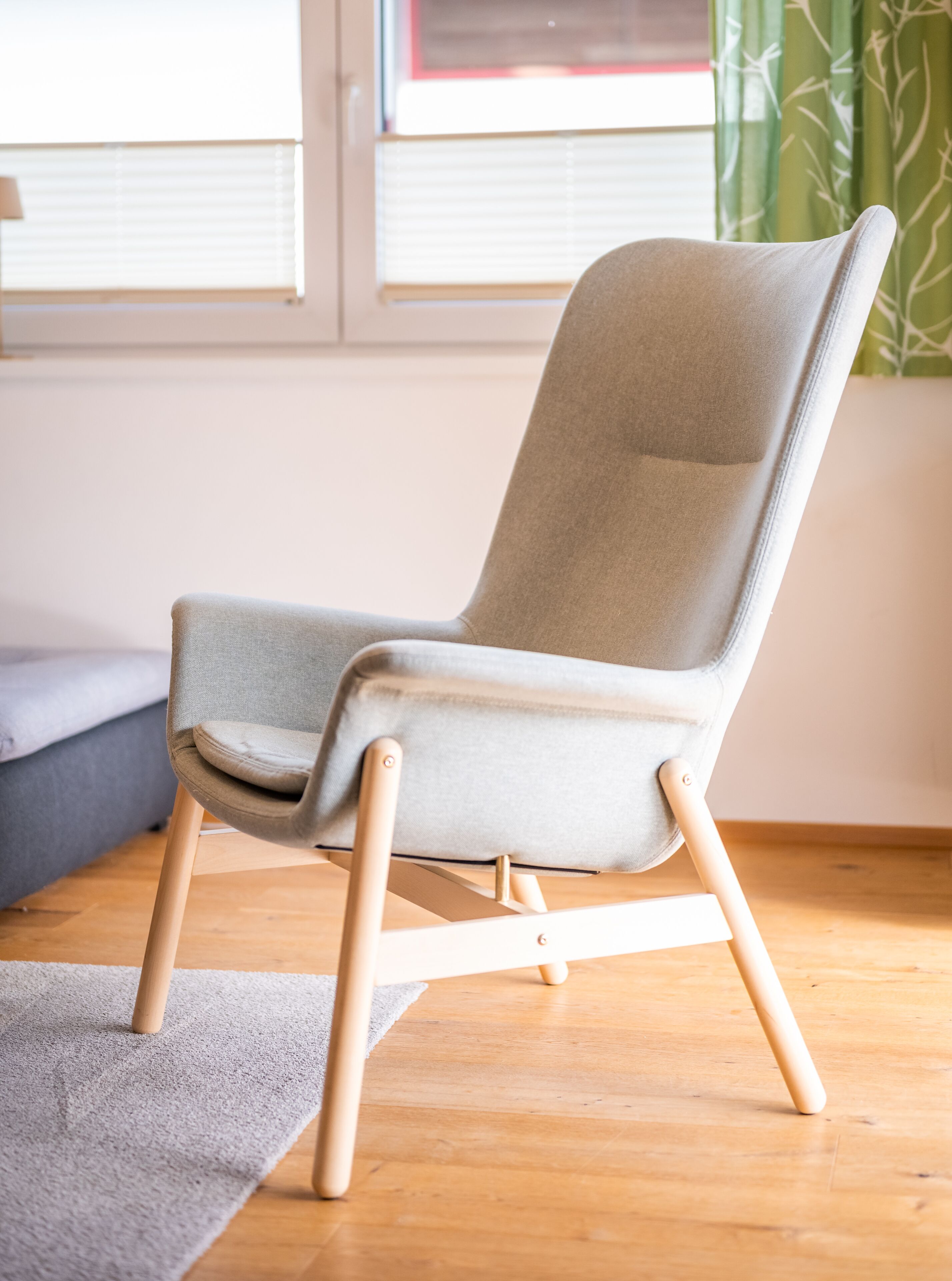 Un fauteuil moderne avec un siège et un dossier en tissu clair, des pieds en bois et un plancher en bois.