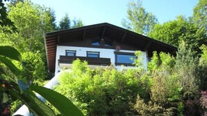 A two-story building with a white facade and dark roof, surrounded by dense greenery. - Chalet Lake View (Zell am See)