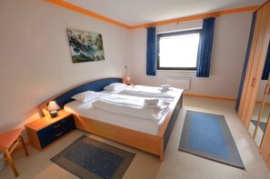 A bedroom with a bed, bedside tables, a lamp, a window with curtains, a painting on the wall, and a wardrobe. - Chalet Lake View (Zell am See)