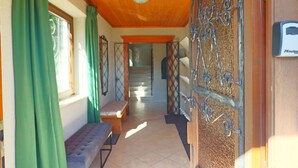 A hallway with a bench, a staircase, and a door with a metal gate. - Chalet Lake View (Zell am See)