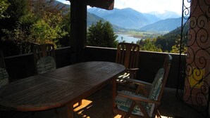 An outdoor patio with a wooden table and chairs, overlooking a mountainous landscape with a lake. - Chalet Lake View (Zell am See)