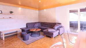 A modern living room with a sectional sofa, a wooden coffee table, and a bench. - Chalet Lake View (Zell am See)