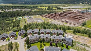 A resort with multiple chalet-style buildings, a parking area, and a large open construction site. - Modern Radium Retreat | Fireplace | Mountain Views (Radium Hot Springs)