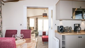 A compact living space with a dining area, kitchen, and a view into the living room.