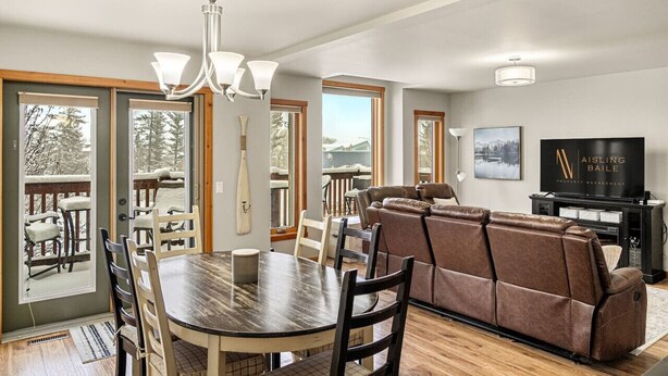 A spacious living room with a large sectional sofa, a dining table with chairs, and a television.