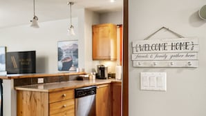 A modern kitchen with wooden cabinets, a dishwasher, and a welcome sign on the wall.