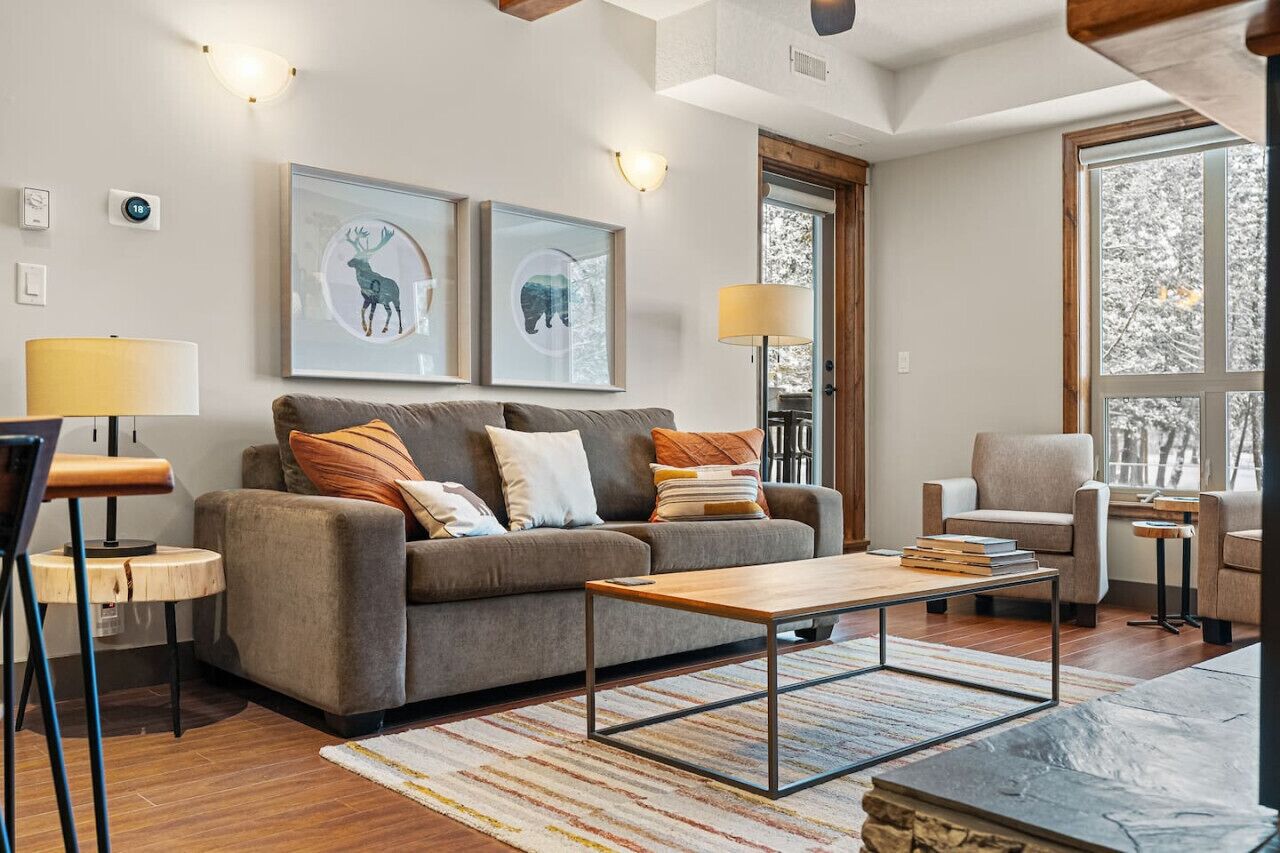 Ein modernes Wohnzimmer mit einer Couch, Sesseln, einem Couchtisch und Kunstwerken an der Wand.