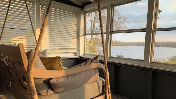 A wooden swing chair with cushions, a rope, and a view of a lake through a window. - Breathtaking Private, Lakefront Retreat.  (Lebanon)