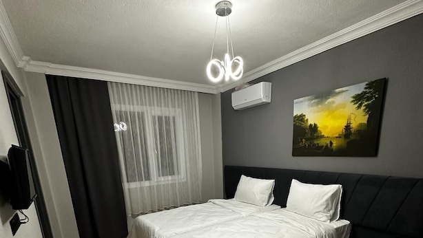 Un dormitorio con cama, mesita de noche, aire acondicionado instalado en la pared y un cuadro.