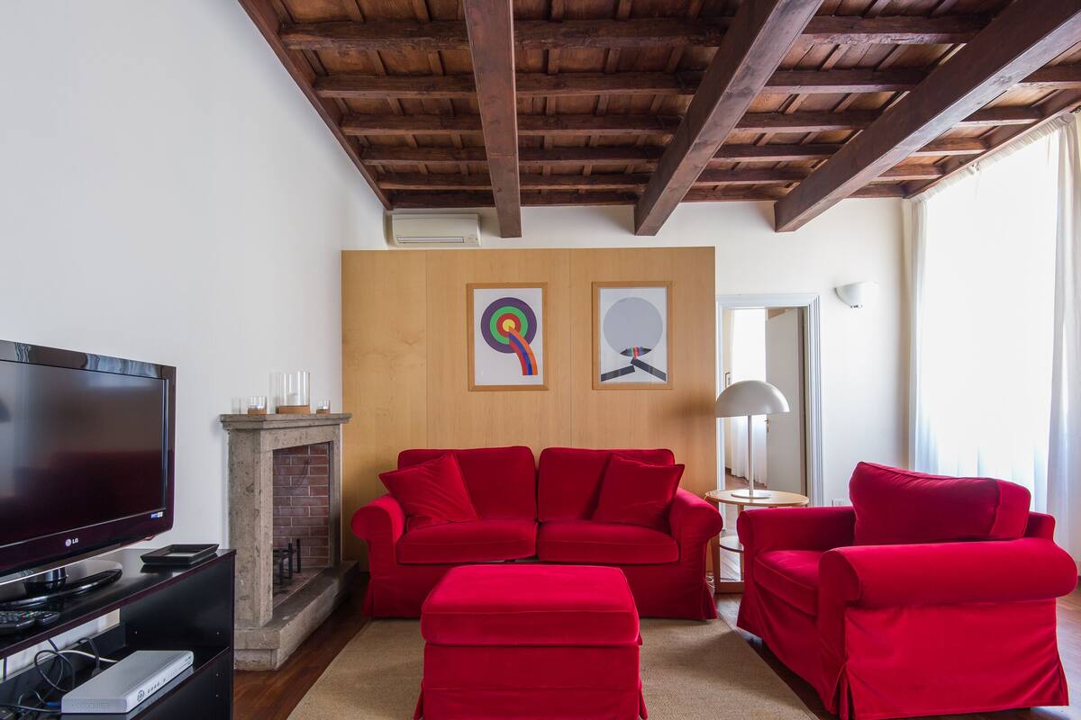 A living room with a red sofa set, a flat-screen TV, and a fireplace.