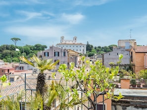A view of a historic town with traditional architecture, including a prominent building with a bell tower, surrounded by lush greenery and residential buildings.
