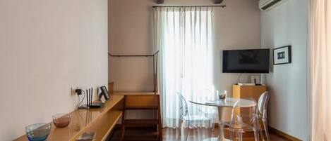 Un salon moderne avec un plafond en bois, un téléviseur à écran plat, une table à manger avec des chaises et un escalier menant à un autre niveau.