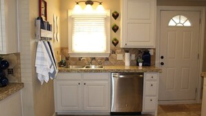 A kitchen with white cabinets, a stainless steel dishwasher, a granite countertop, and a window with blinds. - Spacious one bedroom 2 miles from Texas Tech!

 (Lubbock)