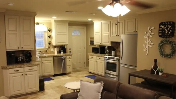 A modern kitchen with white cabinets, a dining area with a brown leather couch, and a ceiling fan. - Spacious one bedroom 2 miles from Texas Tech!

 (Lubbock)