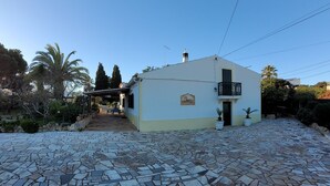 Une maison avec un patio carrelé, une véranda et un petit balcon.