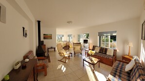 Un salon spacieux comprenant un canapé, des fauteuils, une table basse et un coin repas avec une table et des chaises.