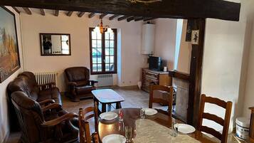 Un salon chaleureux avec une cheminée, des meubles en bois et une table à manger dressée pour quatre personnes.