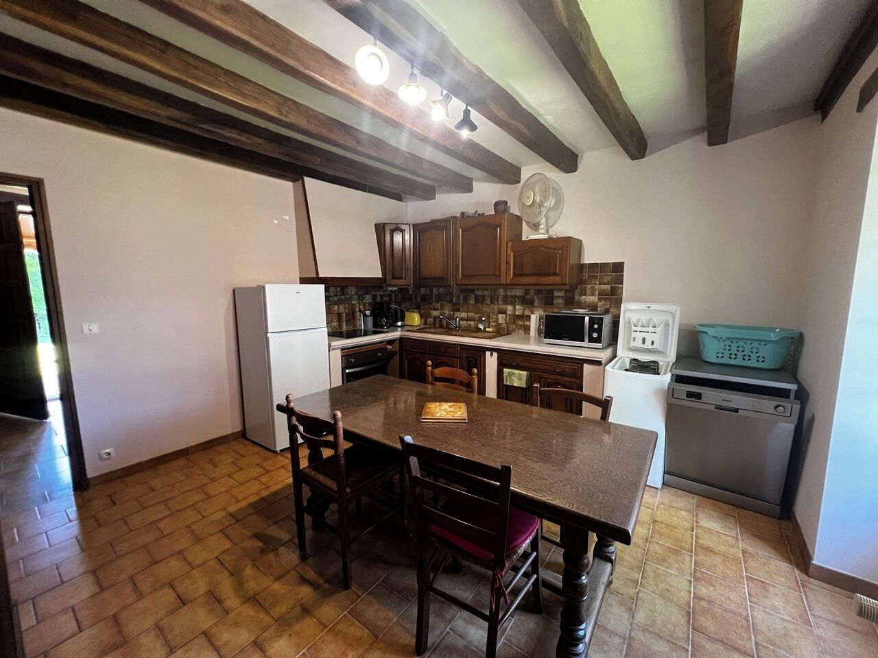 A kitchen with a wooden table, chairs, a refrigerator, a microwave, and a dishwasher.