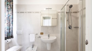 A bathroom with a toilet, bidet, sink, mirror, shower, and a towel rack. - VILL' ANDREA (App. 6) (Cecina)