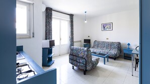 A modern living room with a sofa, a coffee table, a TV, and a dining area with a table and chairs. - VILL' ANDREA (App. 6) (Cecina)