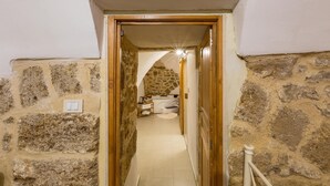 A narrow hallway with stone walls, a wooden door, and a small bathroom with a bathtub and a towel rack. - 3693 Casa Relax by Barbarhouse (Mesagne)