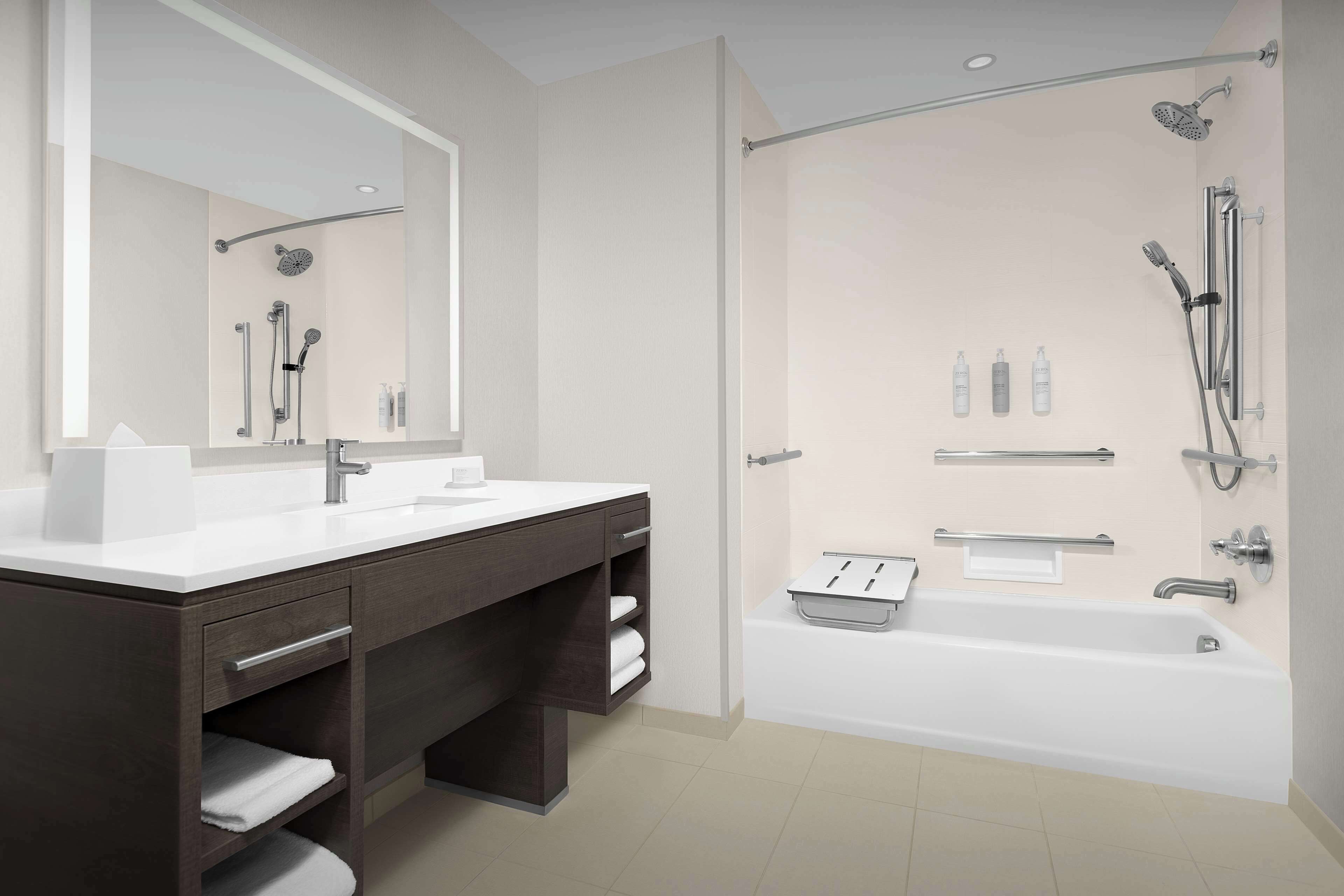 A modern bathroom with a double sink vanity, a large mirror, a walk-in shower with a handheld showerhead, and a bathtub.