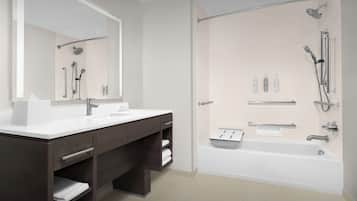 A modern bathroom with a double sink vanity, a large mirror, a walk-in shower with a handheld showerhead, and a bathtub.