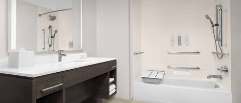A modern bathroom with a double sink vanity, a large mirror, a walk-in shower with a handheld showerhead, and a bathtub.