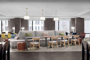 Een moderne eethoek met een lange bank, houten stoelen en hanglampen.