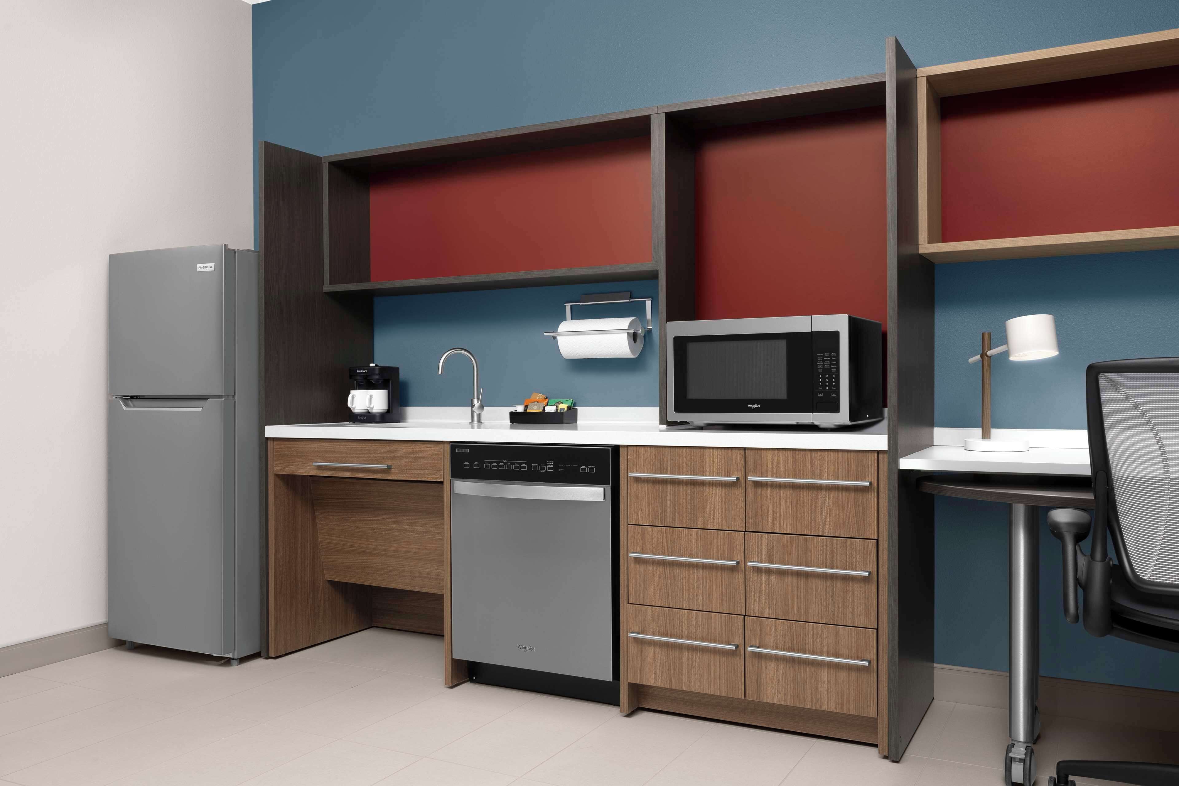 A compact kitchen with a refrigerator, microwave, coffee maker, and dishwasher.