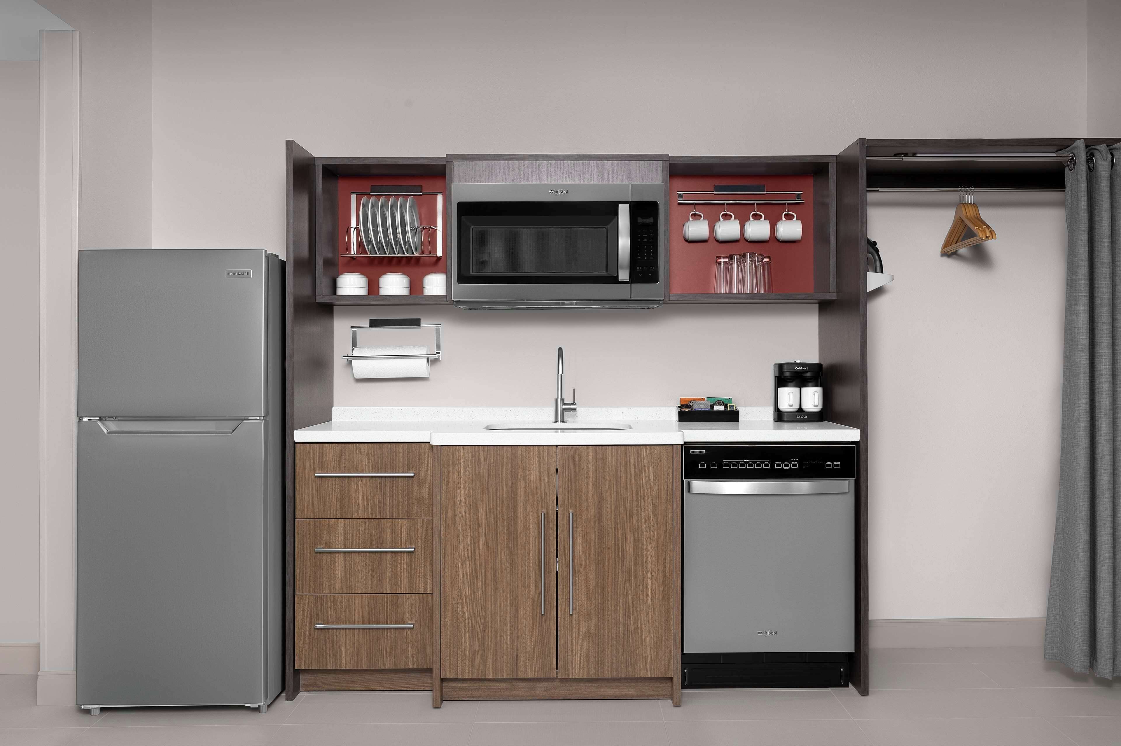 A compact kitchen with a built-in microwave, a dishwasher, and wooden cabinets.