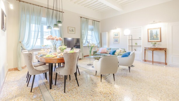 A spacious living room with a dining area, a sofa set, and a television. - Casa Arnolfo in Lucca (Lucca)