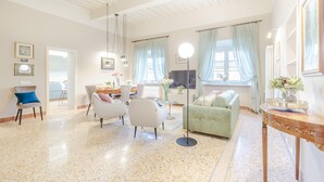 A spacious living area with a high ceiling, a dining area, and a green sofa. - Casa Arnolfo in Lucca (Lucca)