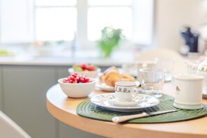 Een ontbijttafel met een kom bessen, een croissant, een kop en een glas.