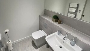 A modern bathroom with a white sink, mirror, and toilet.