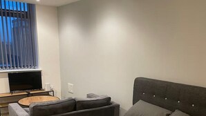 A modern bedroom with a large bed, a sofa, a small table, and a TV.